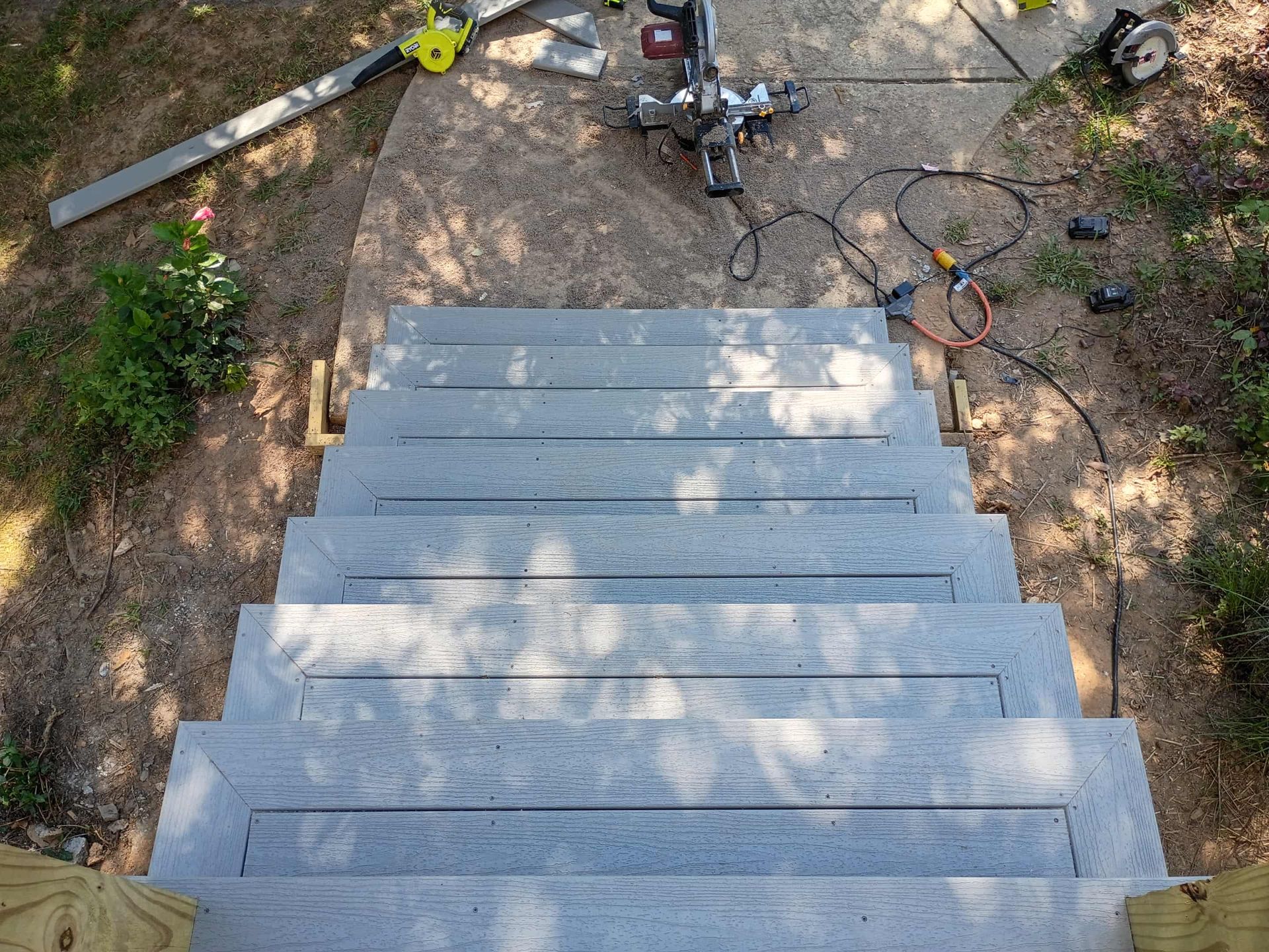 Concrete steps leading to a yard with a chainsaw and tools scattered at the top.