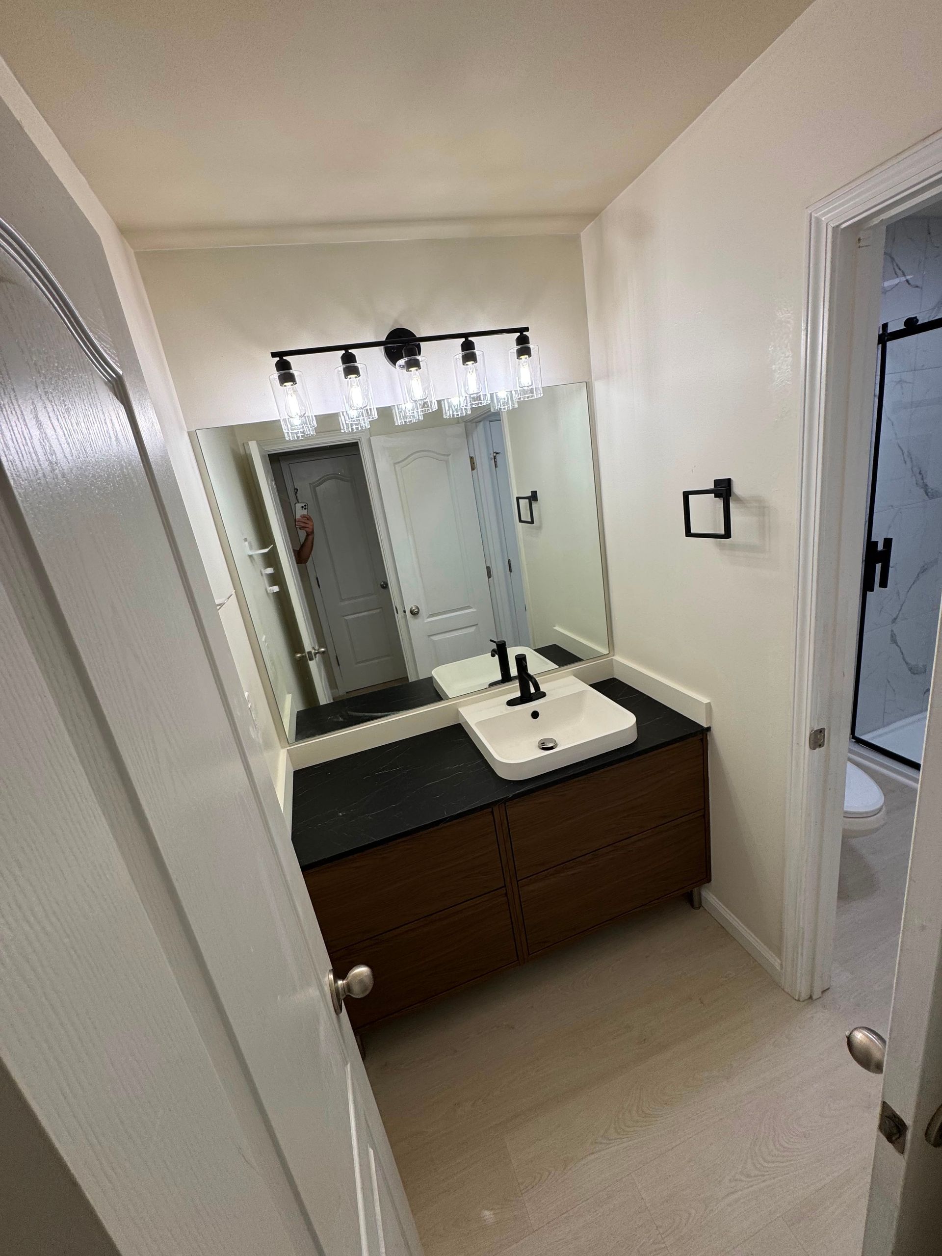 Small bathroom with vanity, sink, mirror, and open doorway to a shower area.