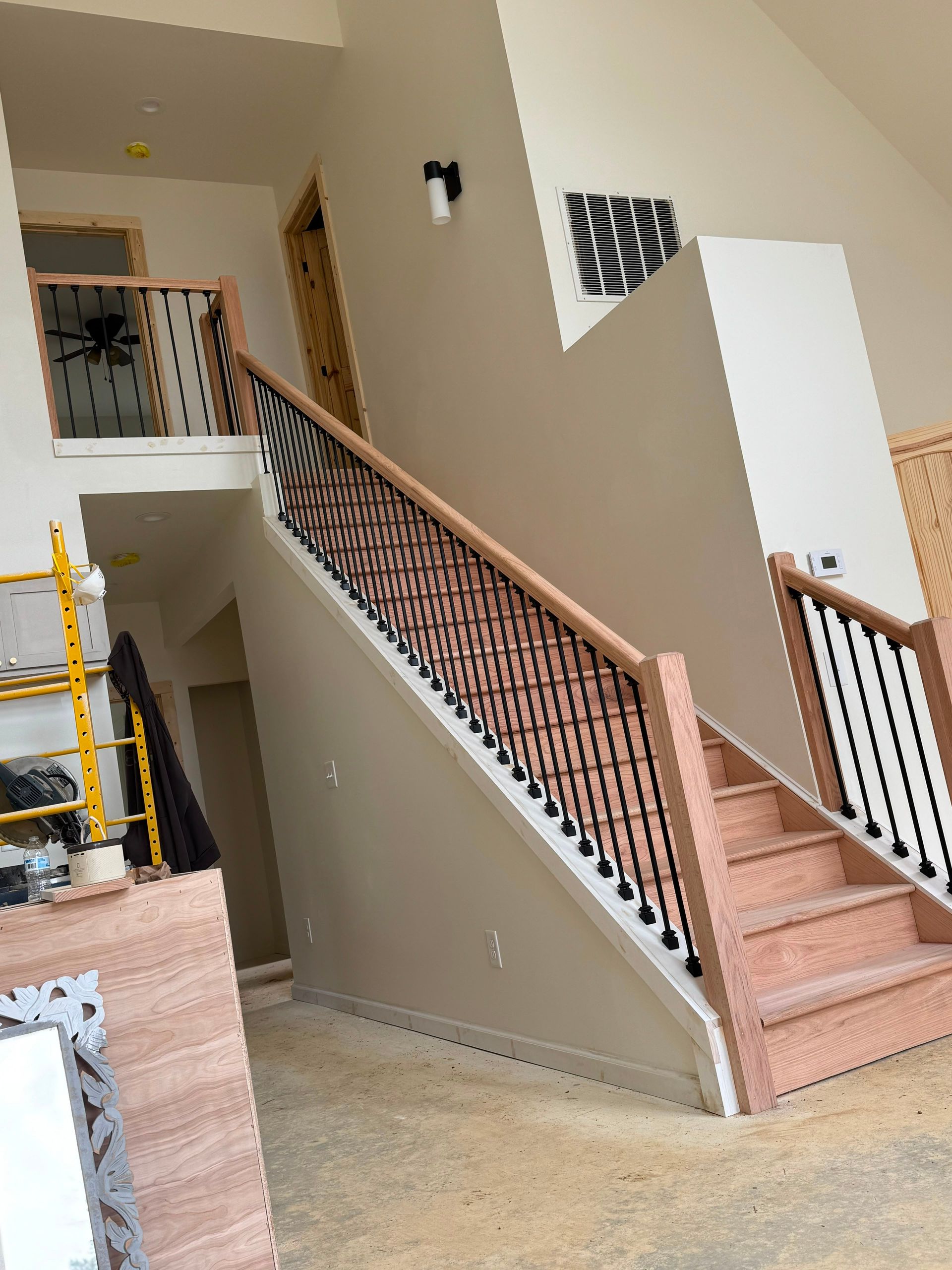 Indoor stairwell with beige walls, pink carpeted stairs, and a patterned black railing.