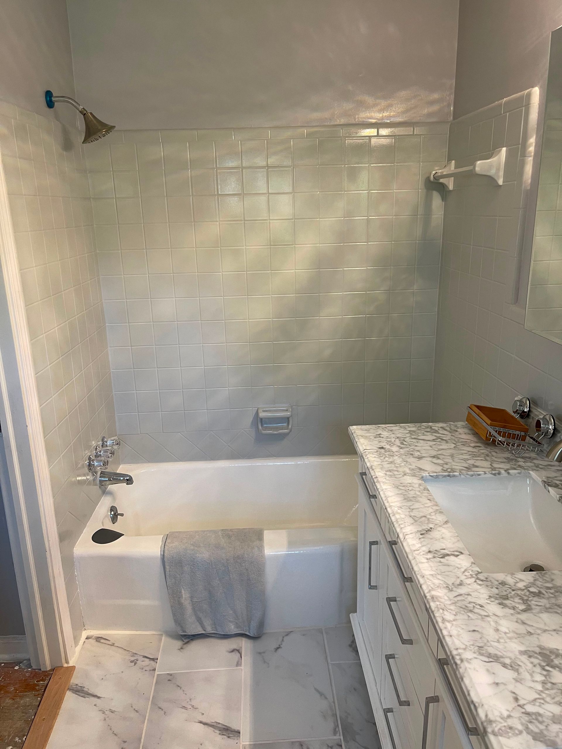 Small bathroom with white subway tile, tub-shower, and granite vanity beside a sink.