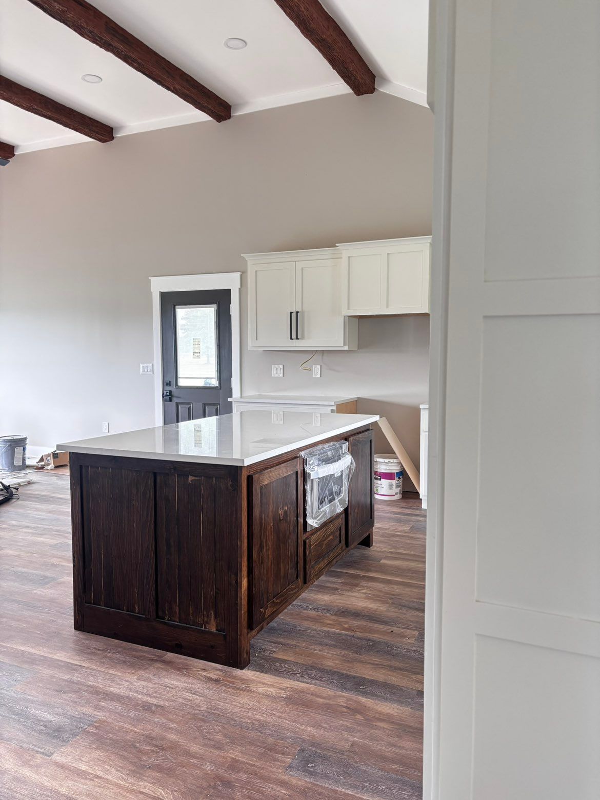 Modern kitchen with white cabinets, dark wood island, and high vaulted ceiling with exposed beams