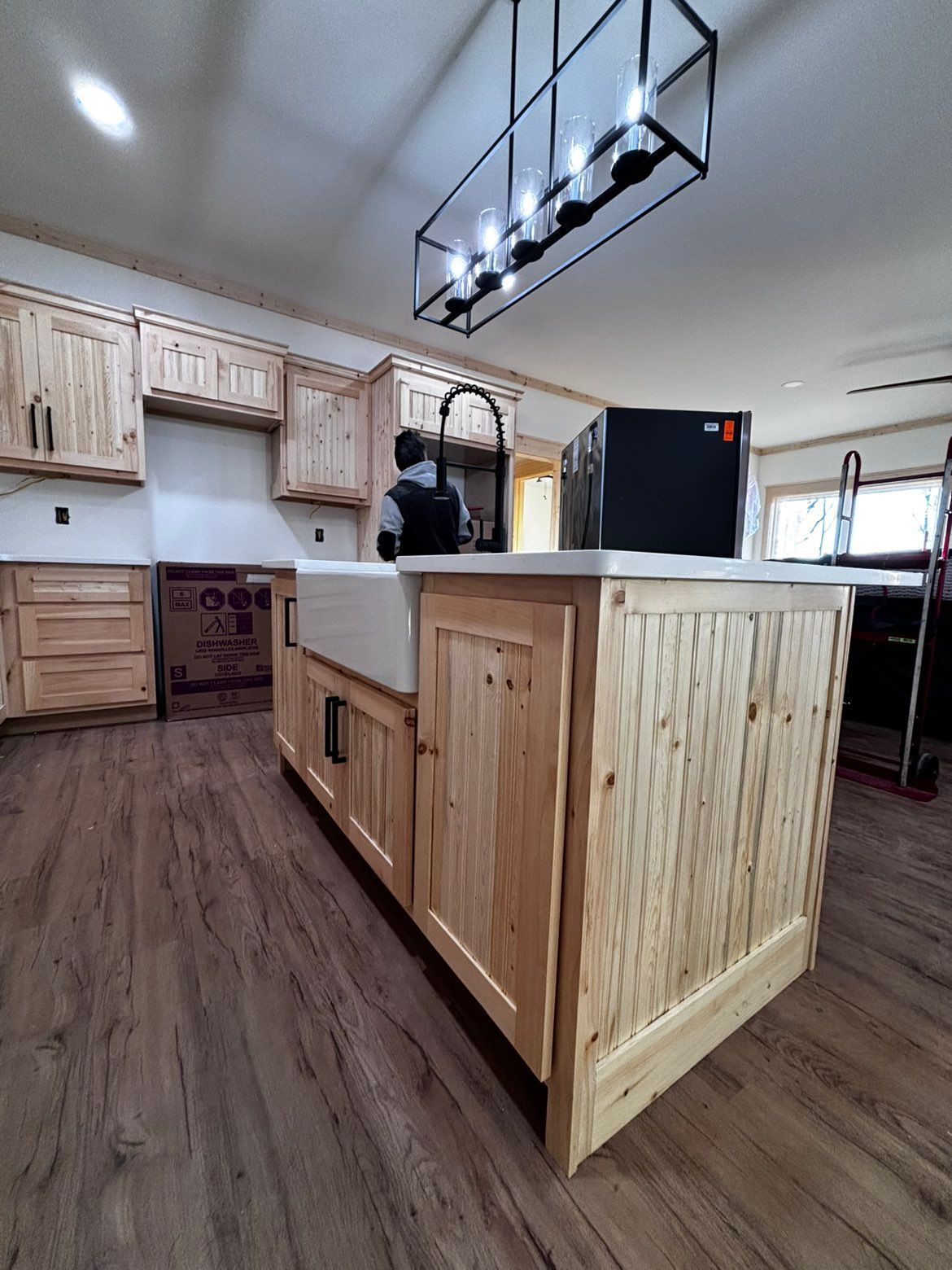 Wooden kitchen island in a bright rustic kitchen with hanging lights and cabinets