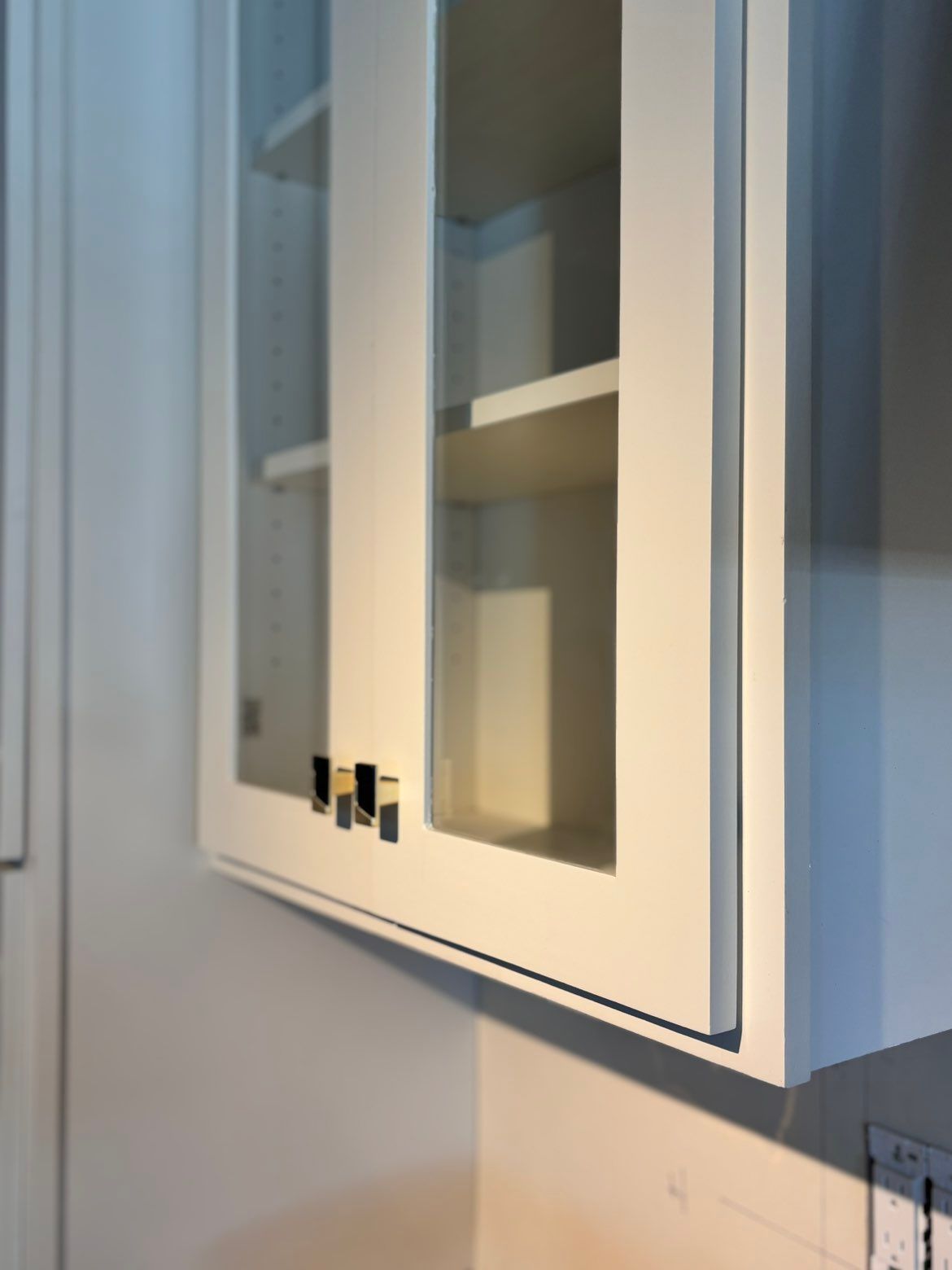 White wall cabinet with glass doors and shelves in a kitchen or bathroom