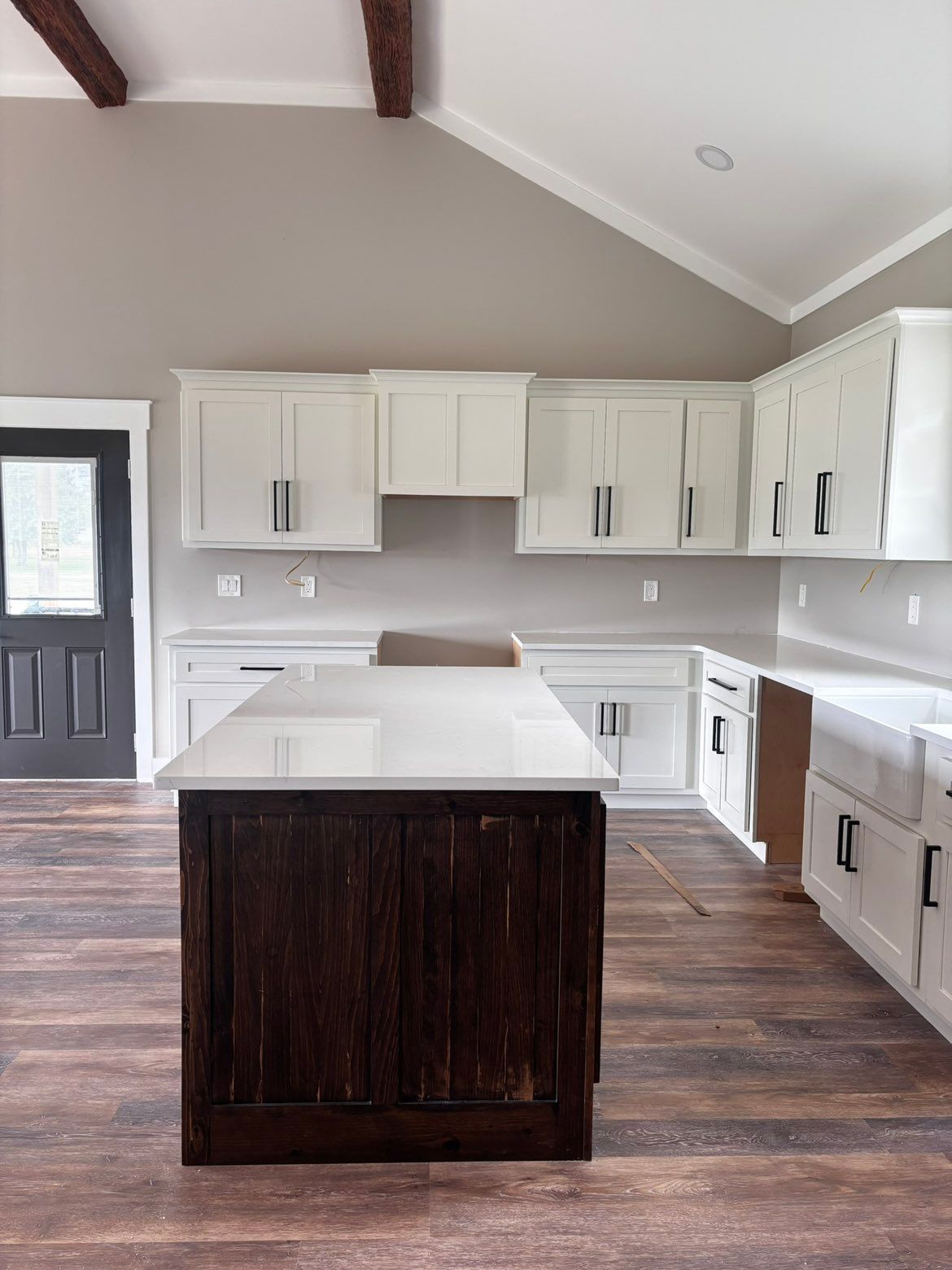 Bright kitchen with white cabinets, dark wood island, and vaulted ceiling
