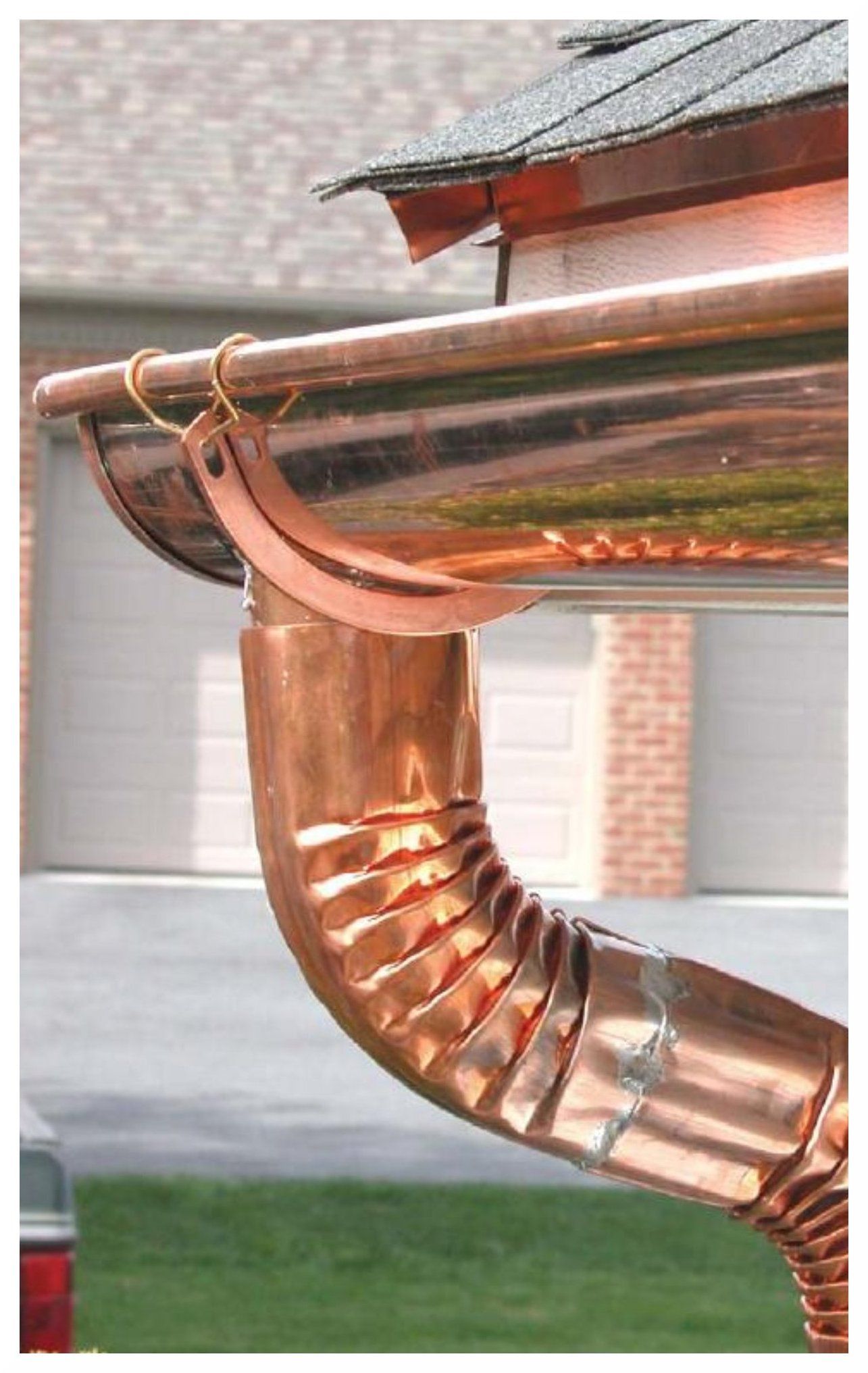 Copper rain gutter and downspout attached to a house roofline