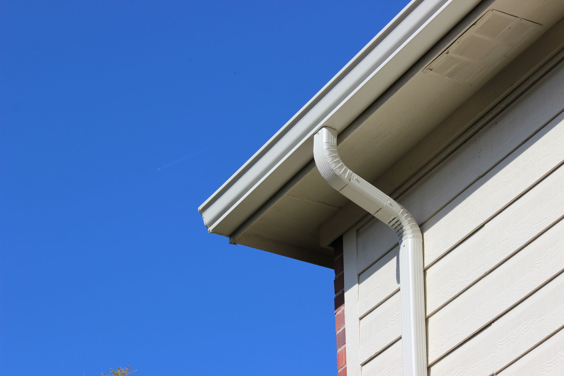 House gutter and downspout against a clear blue sky