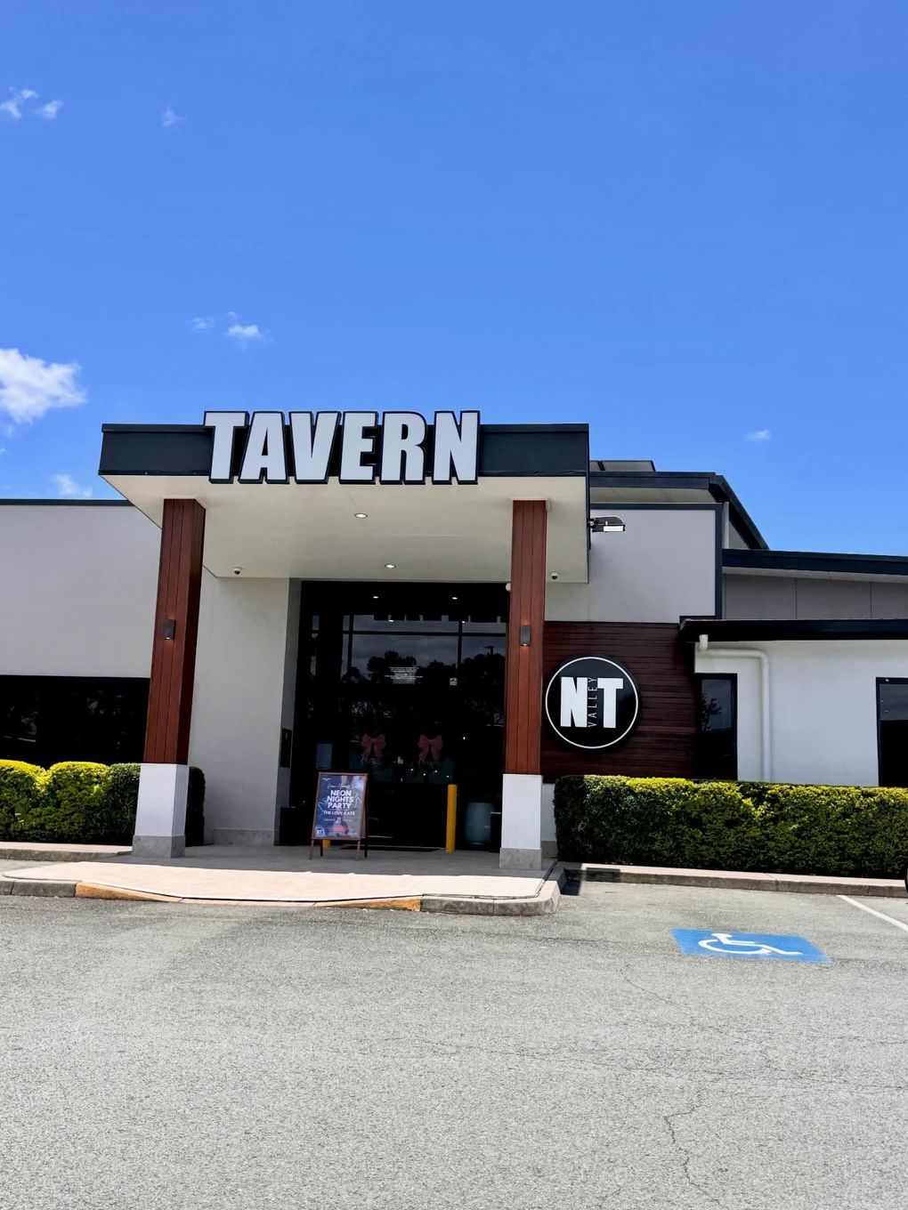Front entrance of a Tavern restaurant with white walls, dark trim, and a blue sky overhead