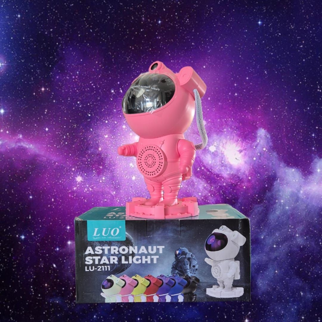 Proyector de luz de estrellas de color rosa con forma de astronauta sobre una caja.