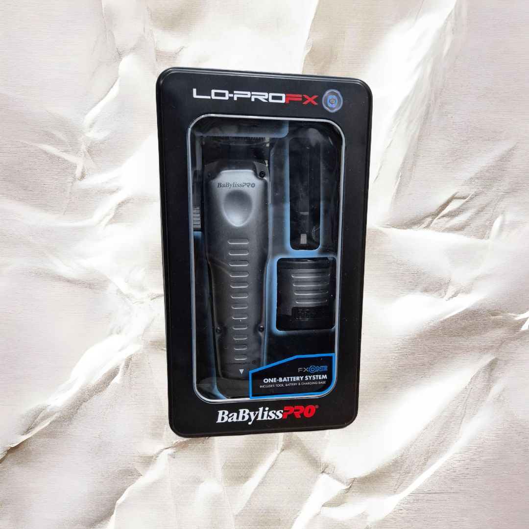 Un cortapelos Babyliss Pro LO PRO FX negro y plateado en su embalaje, sobre un fondo de papel arrugado.