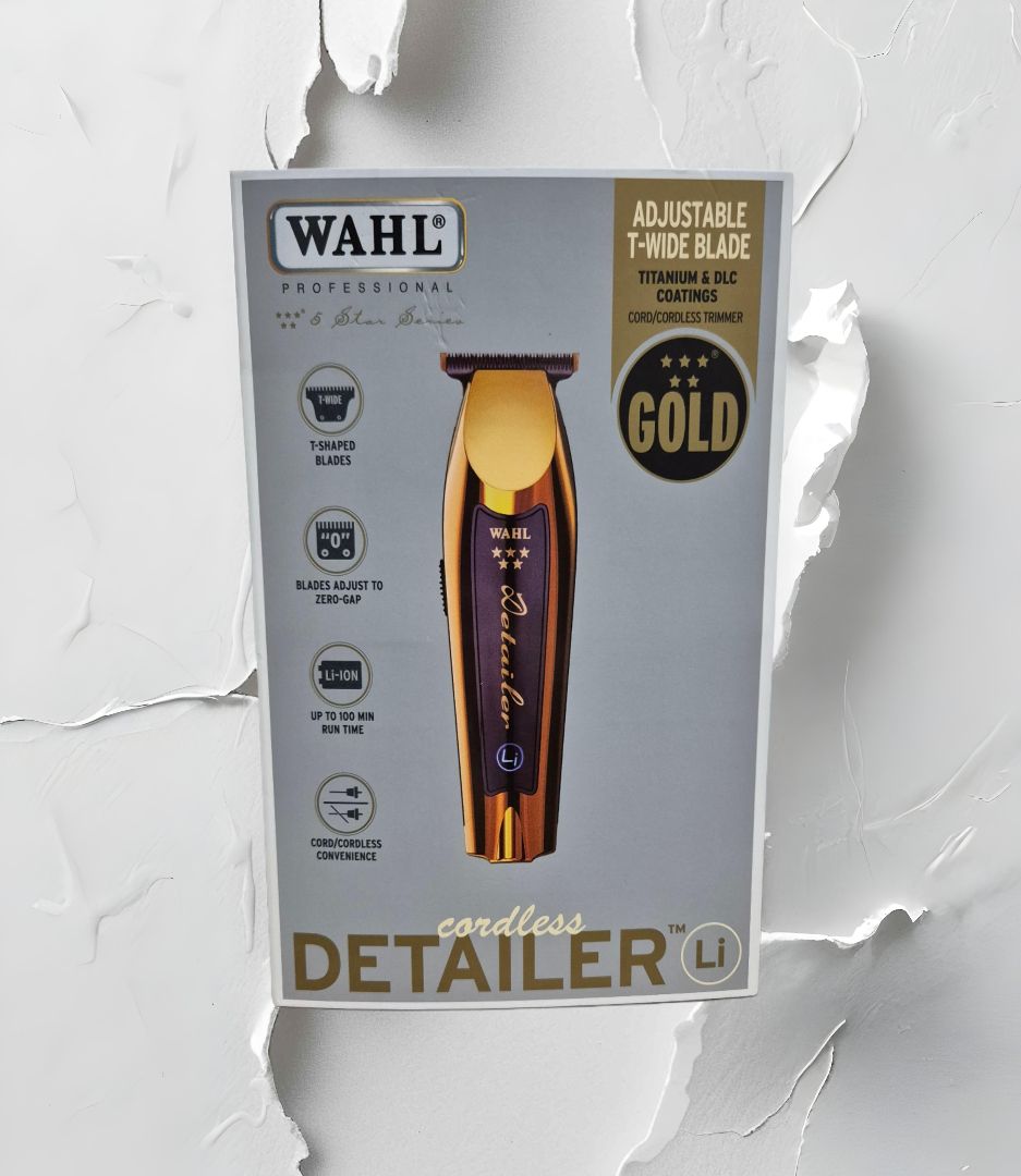 Caja de cortadoras de detalles inalámbricas Wahl en dorado y marrón sobre un fondo blanco texturizado.