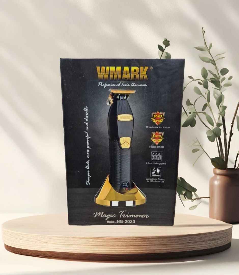Caja de una recortadora mágica WMARK negra y dorada sobre una plataforma de madera, con una planta al fondo.