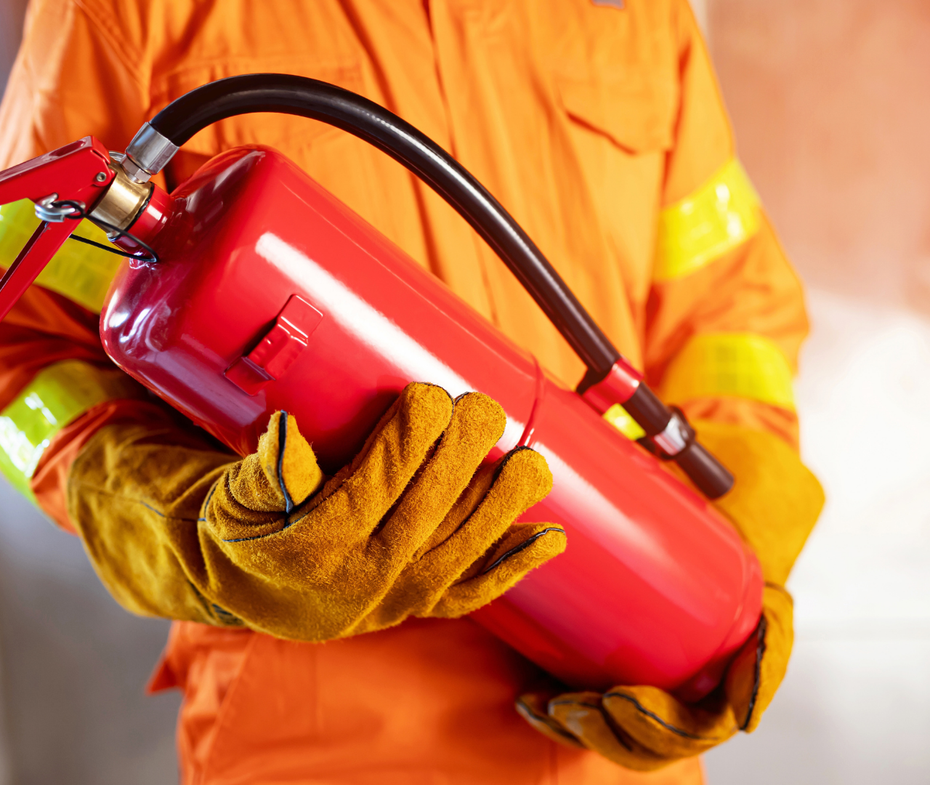 A man wearing gloves is holding a red fire extinguisher