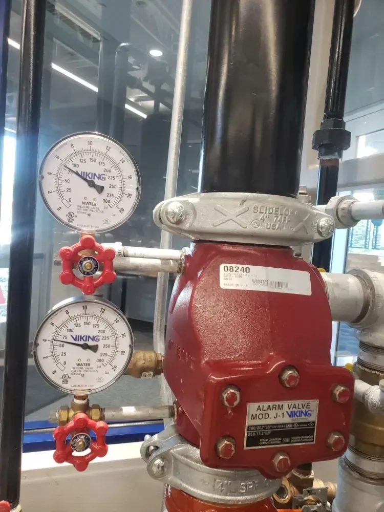 A close up of a fire alarm valve with two gauges attached to it.