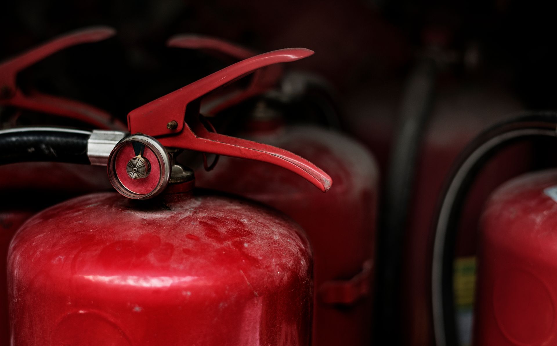 A close up of a red fire extinguisher on a black background.