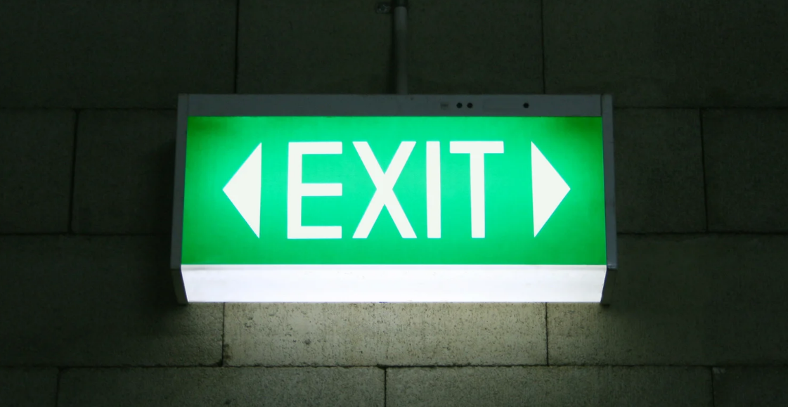 A green exit sign is lit up on a brick wall
