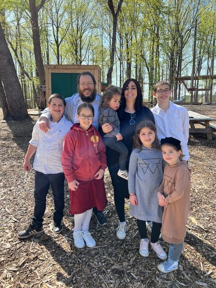 A family is posing for a picture in the woods.