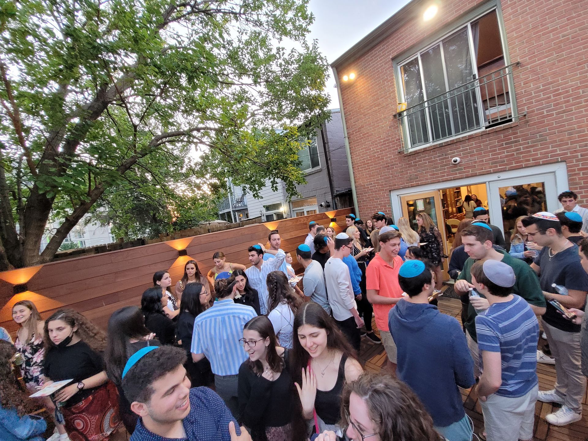 A large group of people are standing in front of a brick building.