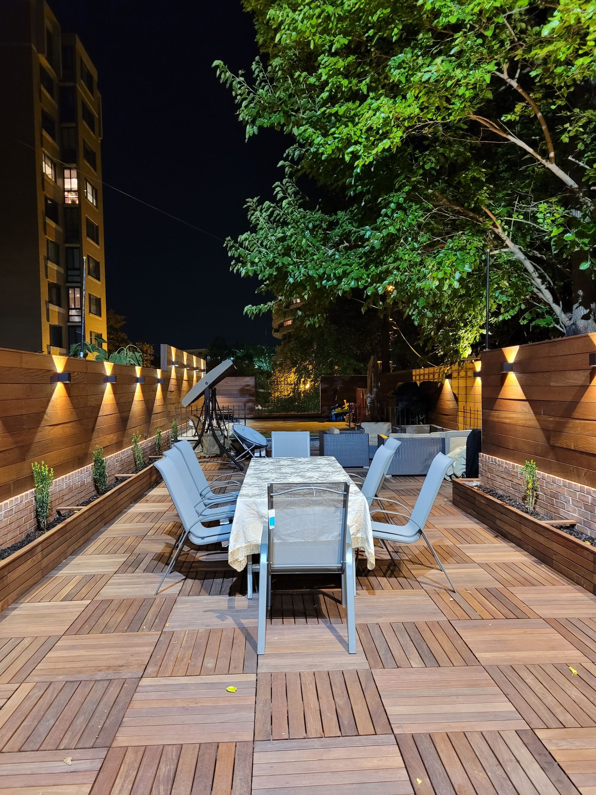 A wooden patio with a table and chairs at night.