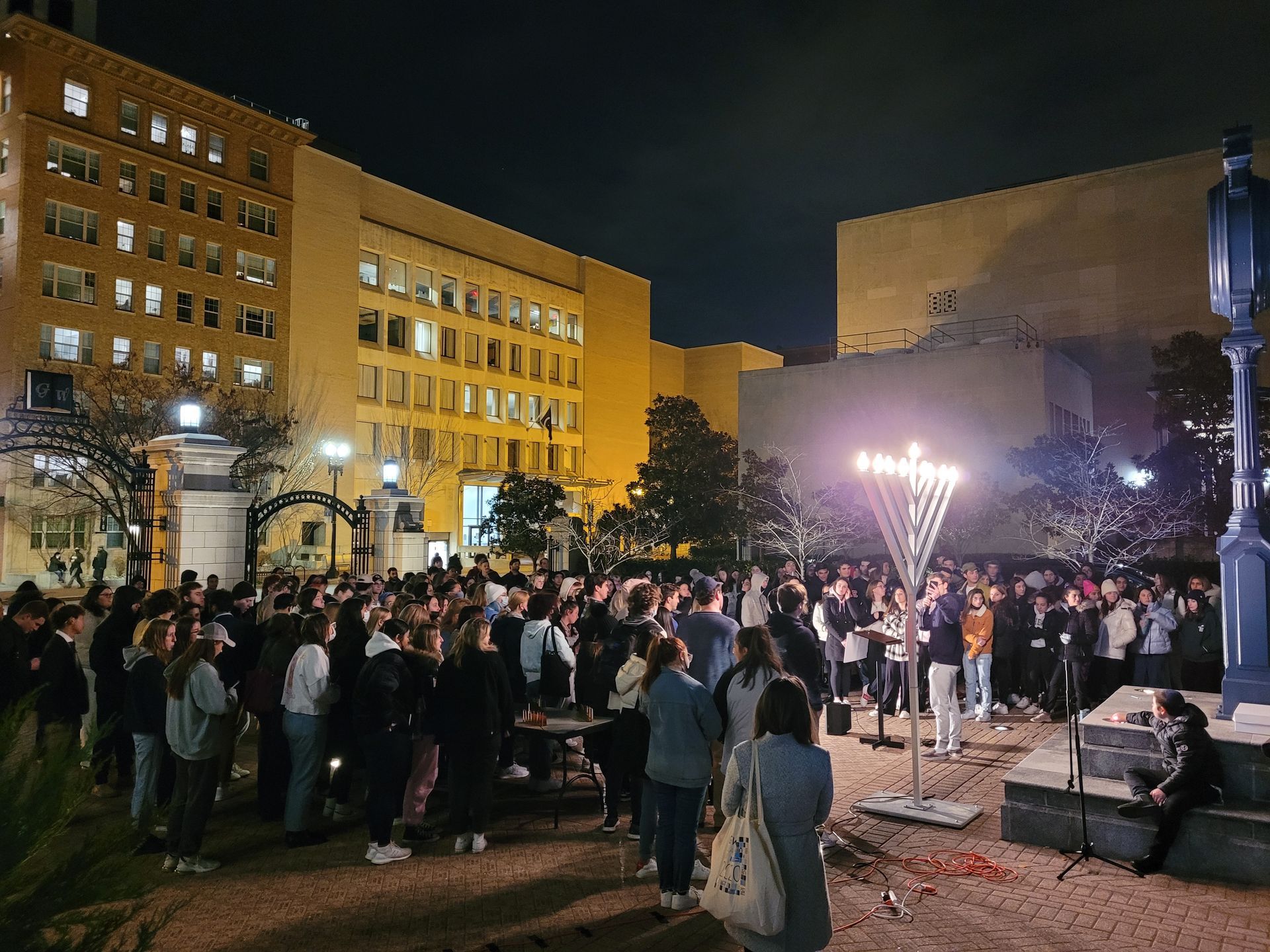A large group of people are gathered in a park at night.