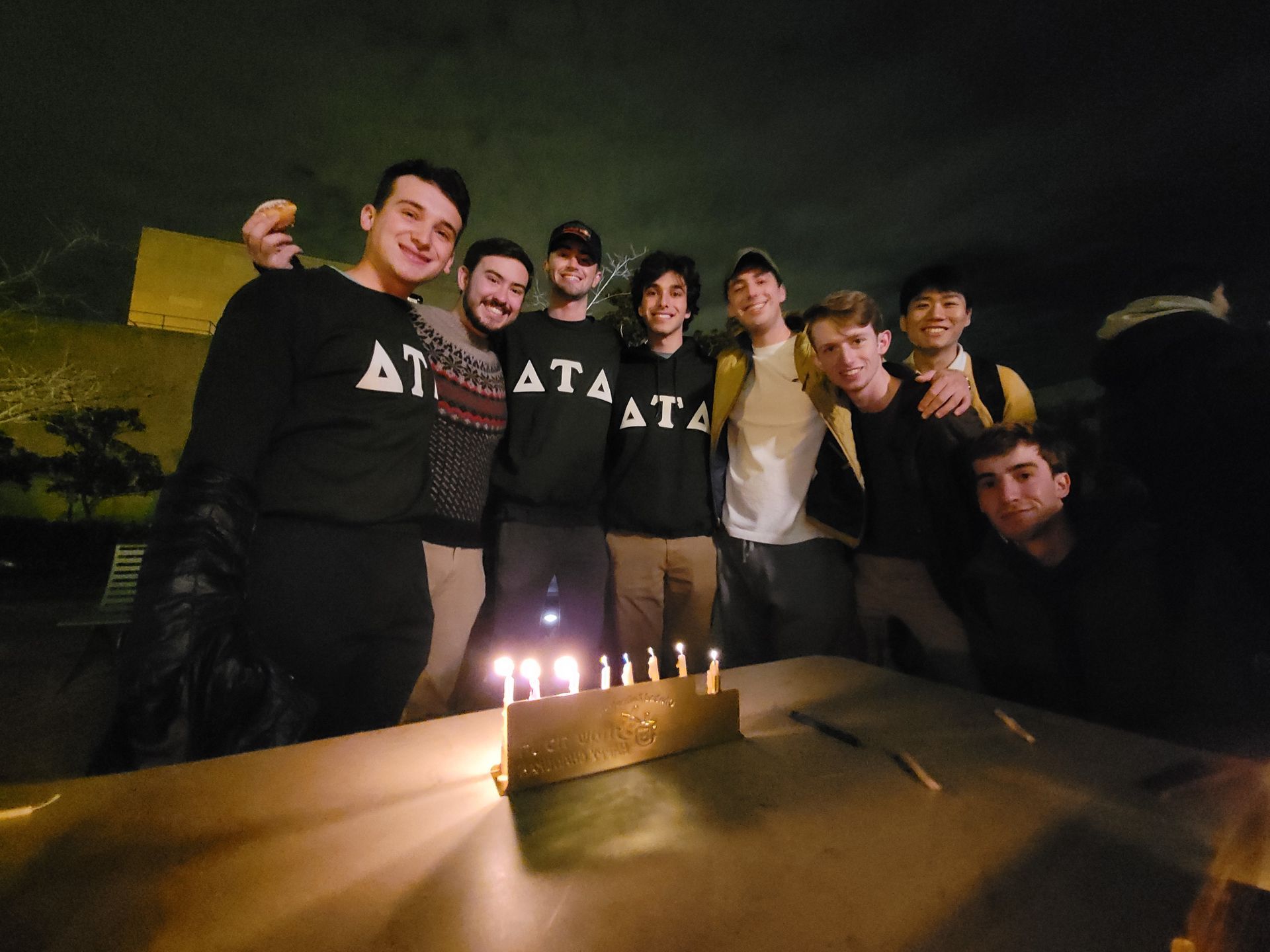 A group of men standing around a table with candles on it.