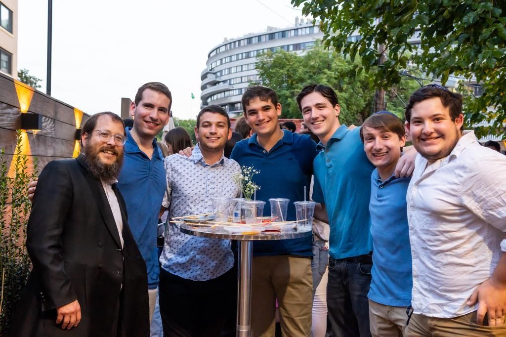 A group of young men are posing for a picture while standing around a table.