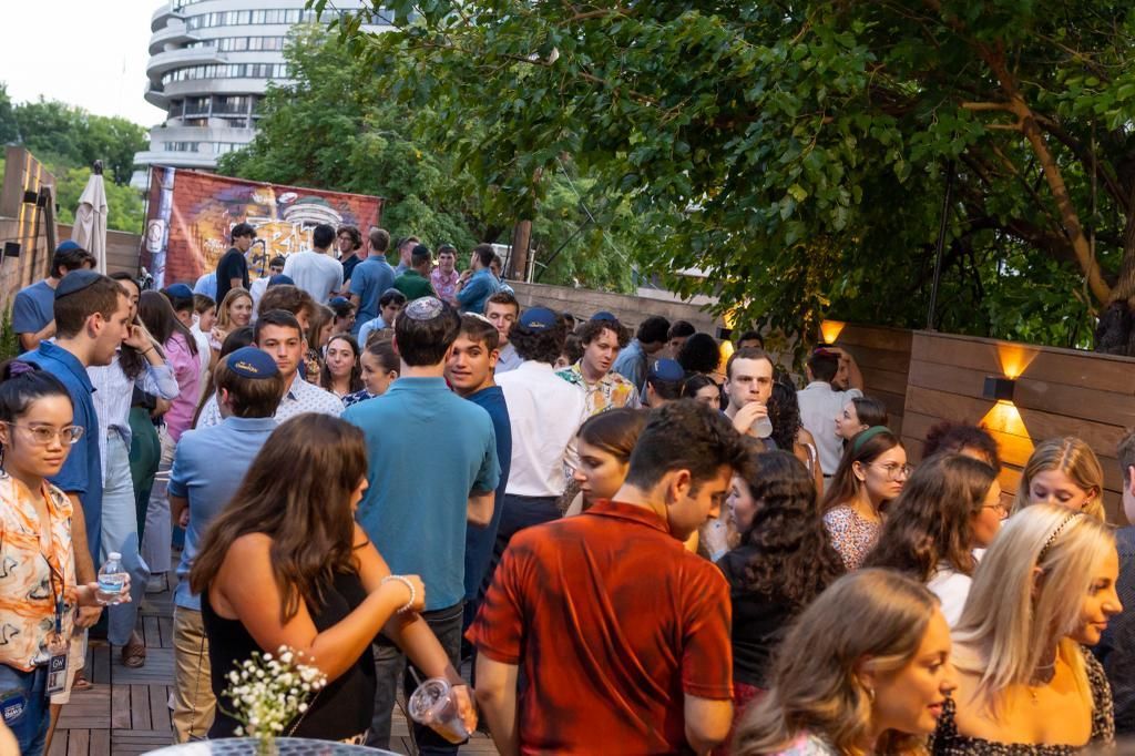 A large group of people are standing around a table at a party.