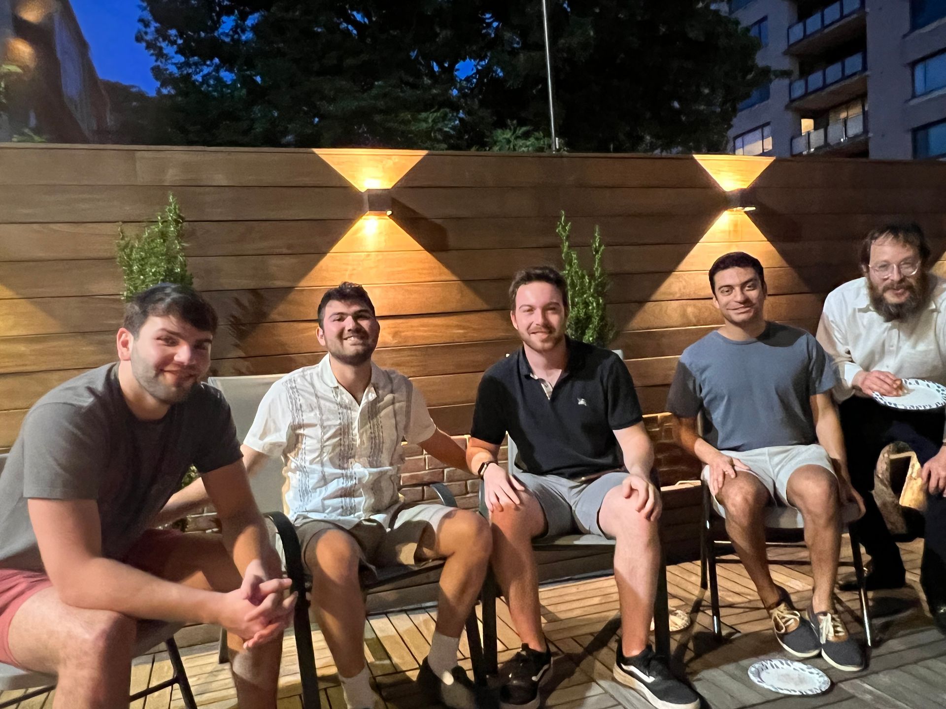 A group of men are sitting in chairs on a patio.