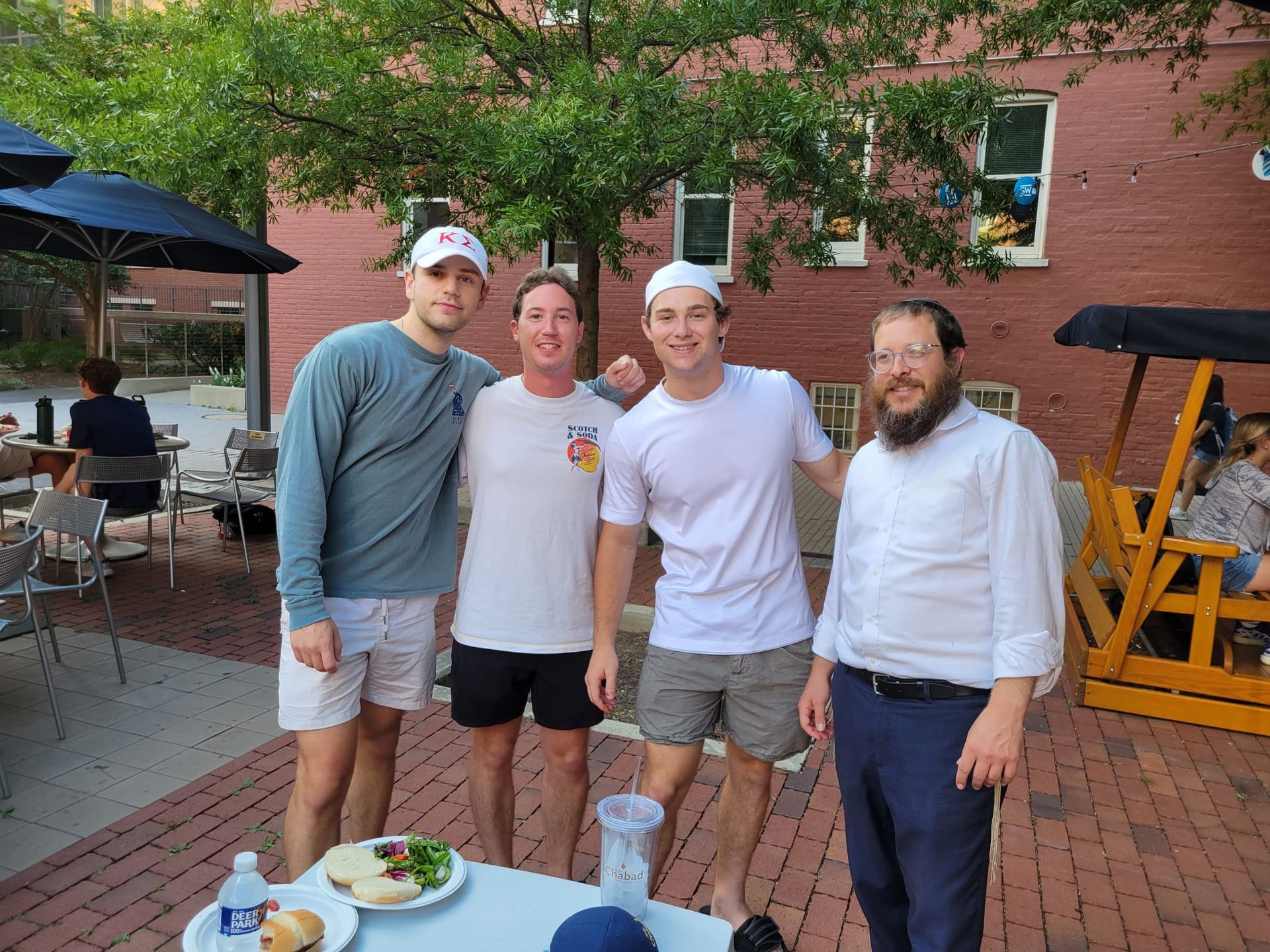 A group of young men are posing for a picture in front of a brick building.