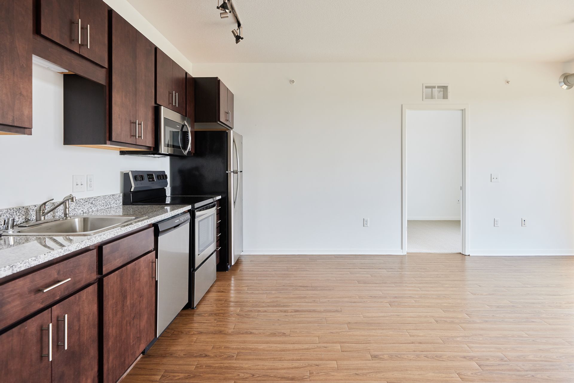 Kitchen with dark wood cabinets, stainless steel appliances, and hardwood floors.