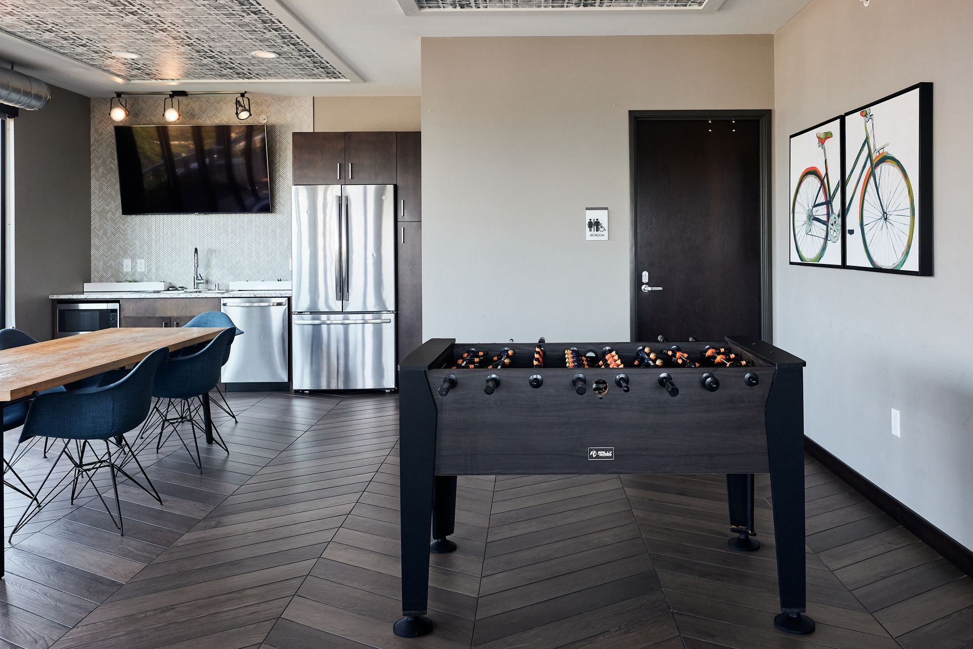 Foosball table in a modern lounge with a dining table, kitchen, and bicycle art.