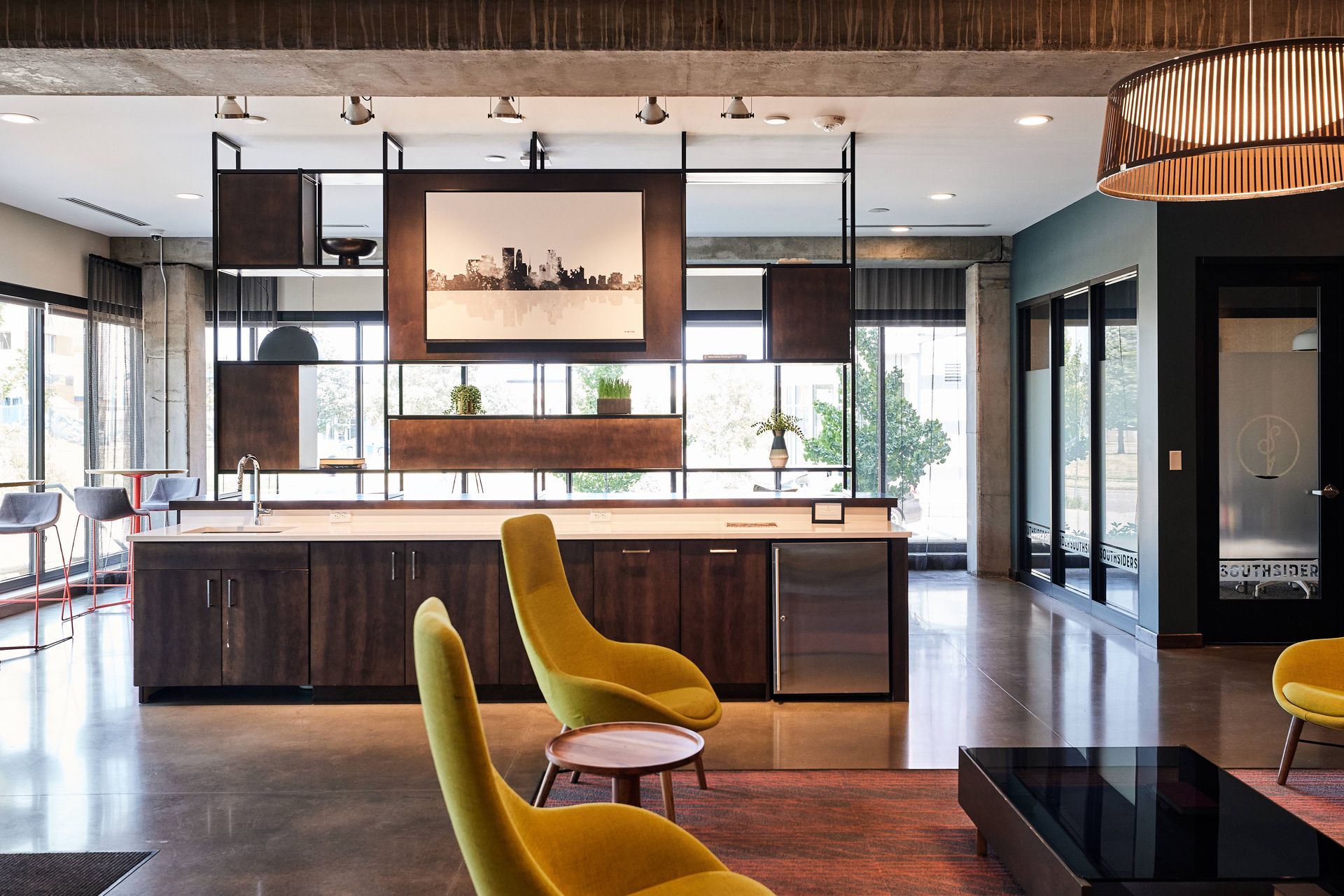 Modern open-concept space with yellow chairs, dark wood cabinets, and an open shelving unit.