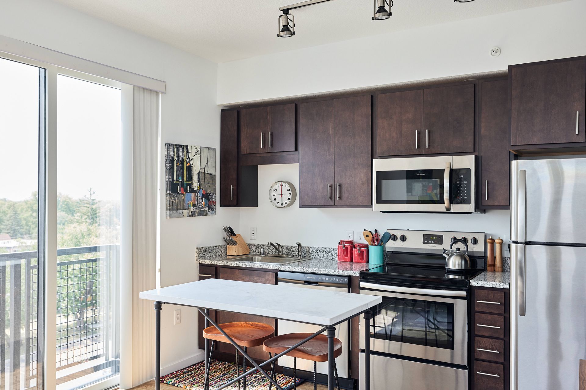 Modern kitchen with dark brown cabinets, stainless steel appliances, and a small breakfast bar.