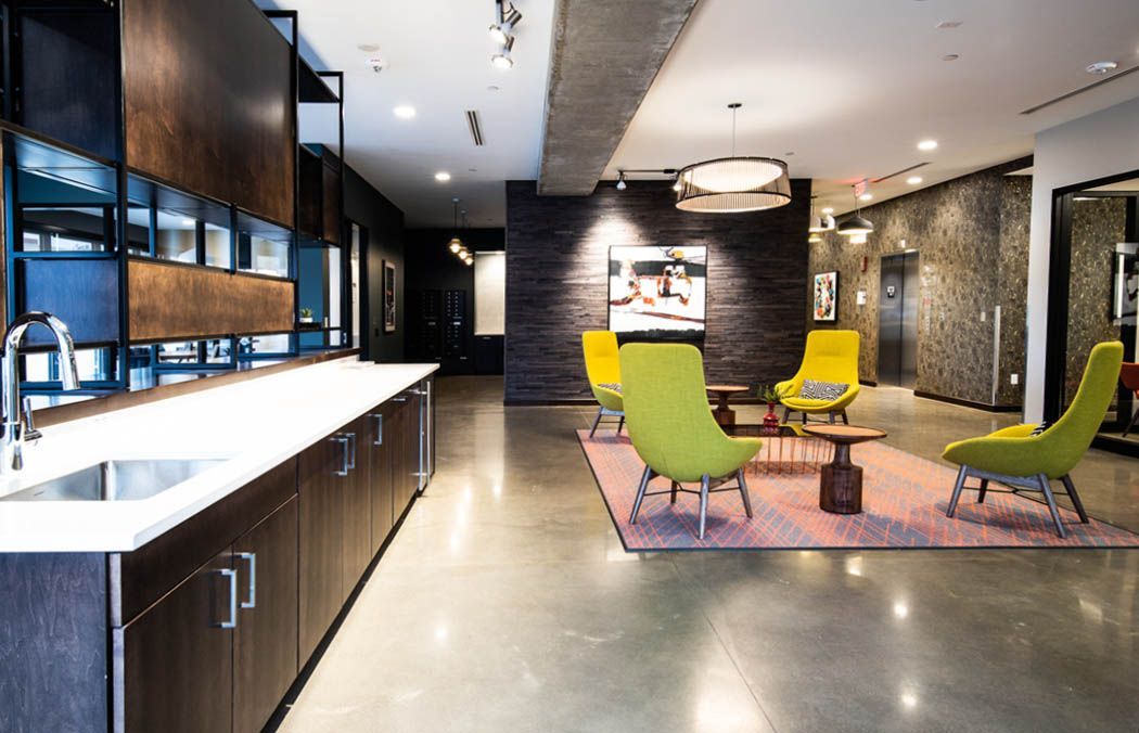 Modern lounge with lime green chairs, a pink rug, and a dark wood accent wall.