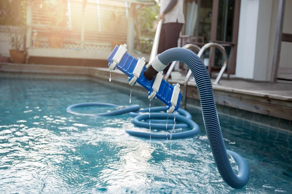 A Man Is Cleaning A Swimming Pool With A Vacuum Cleaner — All Bright Pool Care In Laurieton, NSW
