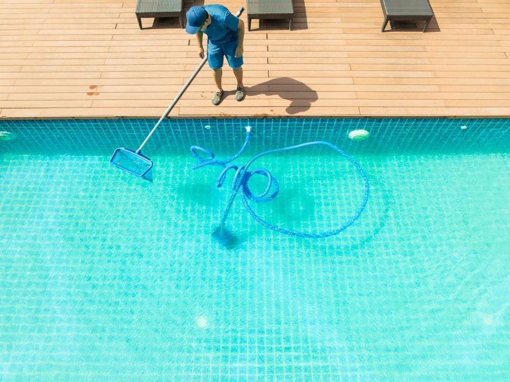 A Man Is Using A High Pressure Washer To Clean A Swimming Pool — All Bright Pool Care In Laurieton, NSW
