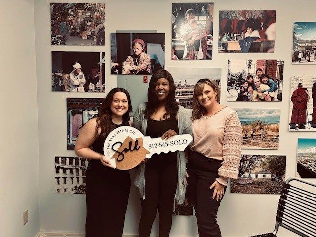 Three women holding a key that says sell on it