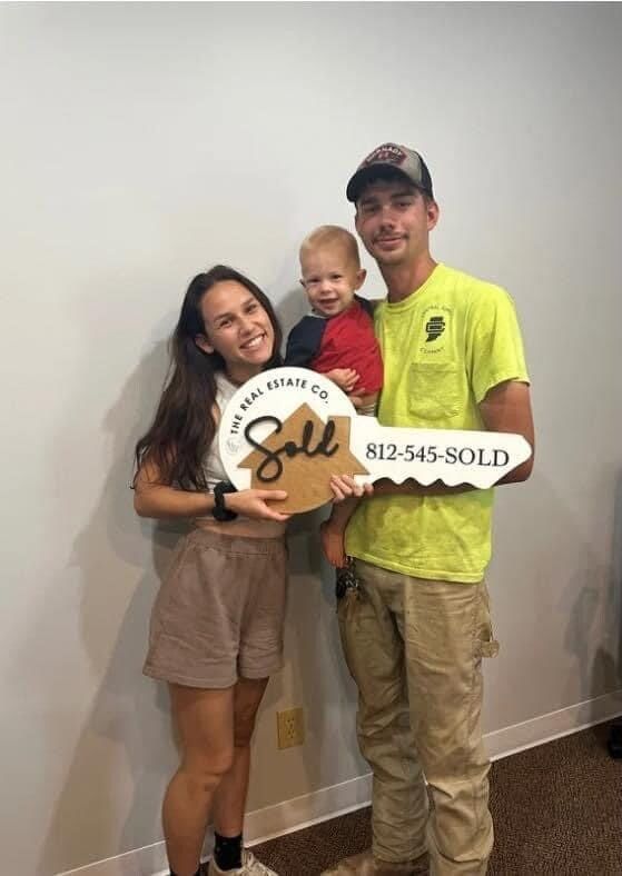A man and a woman are holding a baby and a key.