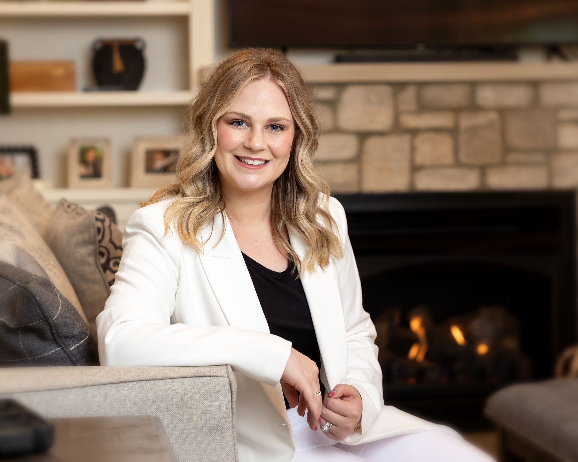 A woman is sitting on a couch in front of a fireplace.