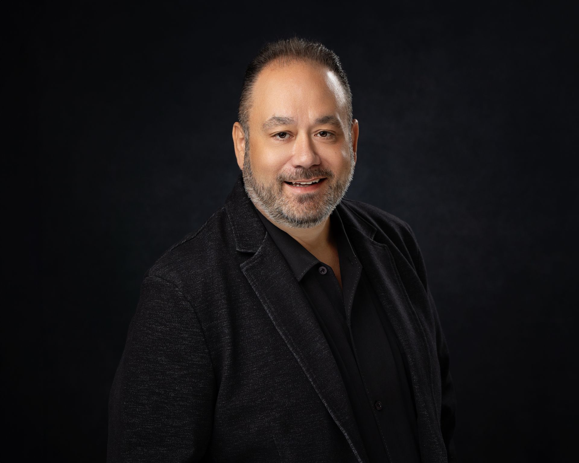 A man in a suit is talking to two people in front of a building.
