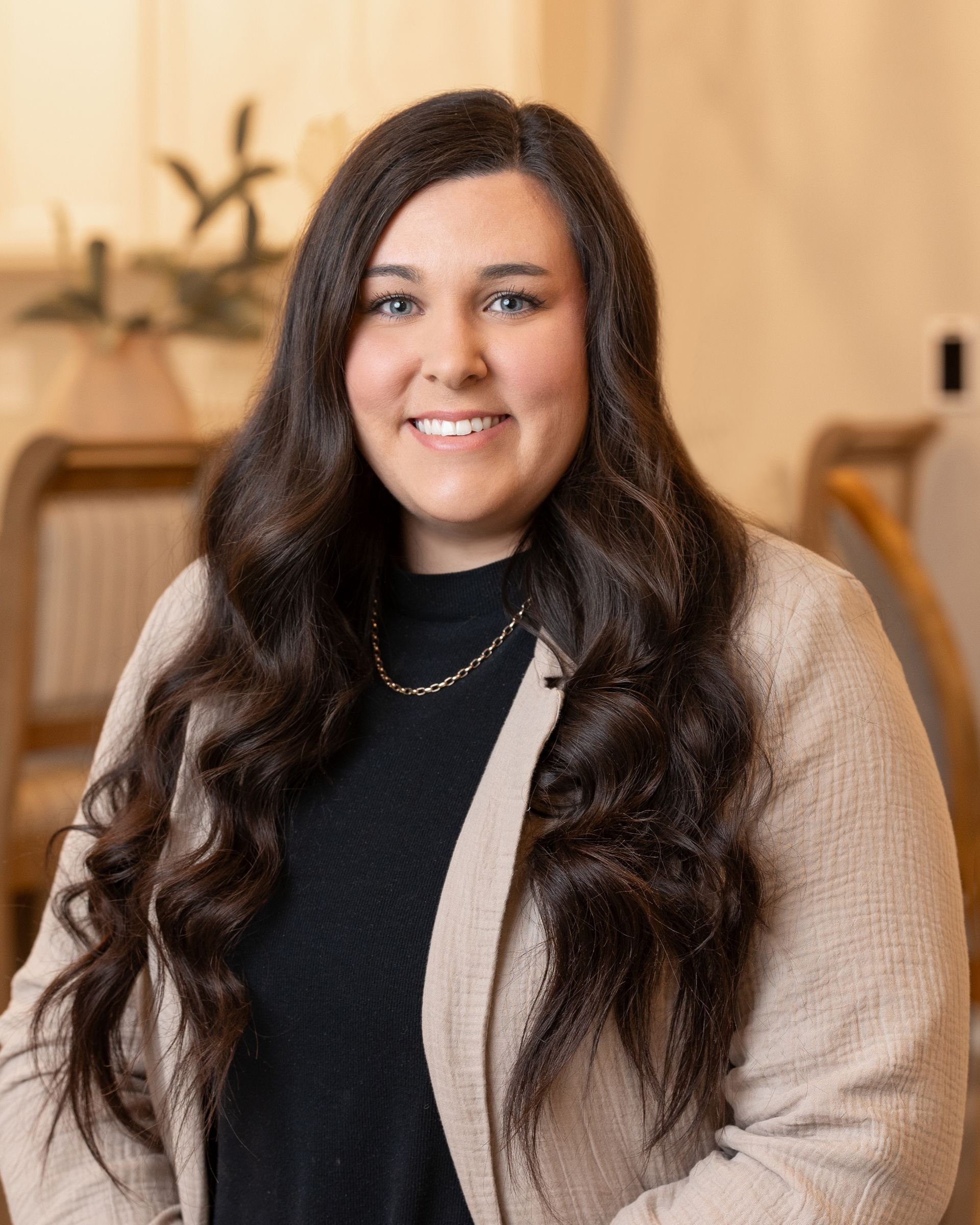 A woman with long hair is smiling for the camera while wearing a sweater and a black shirt.