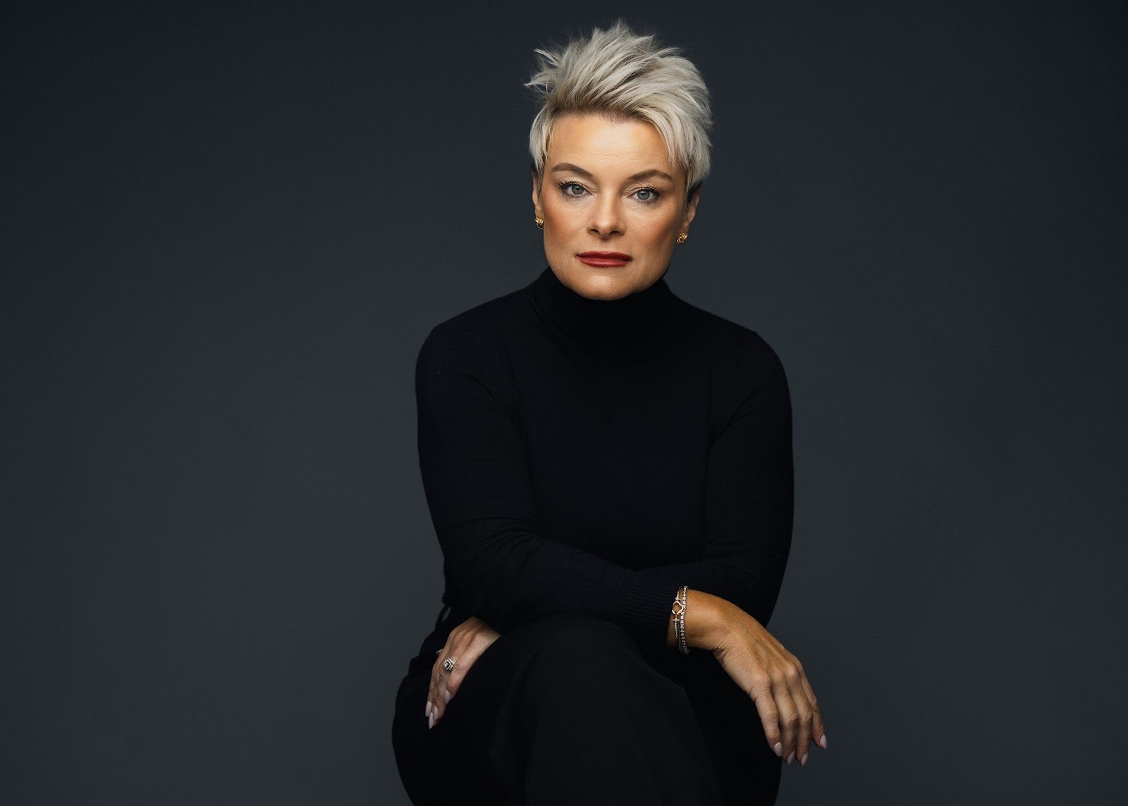 A woman is holding a clipboard and a home for sale sign