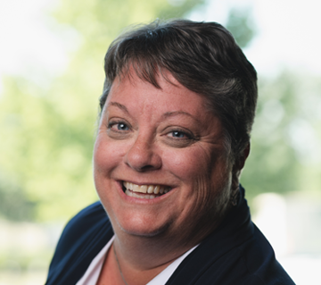 A woman wearing a striped turtleneck and earrings is smiling for the camera.