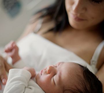 A woman is holding a newborn baby in her arms.