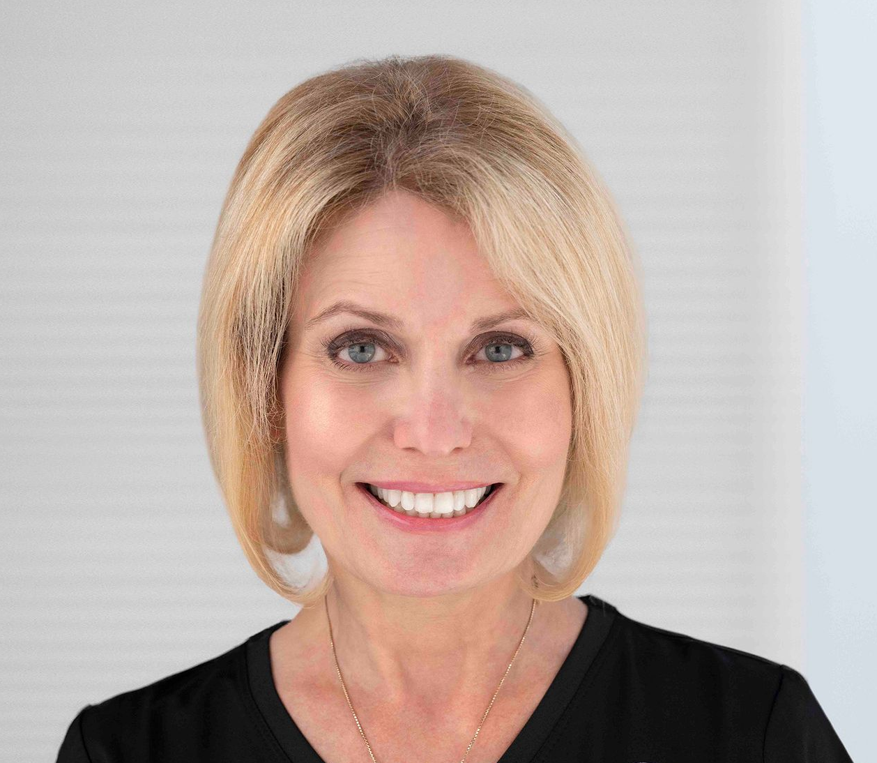 A woman in white shirt smiles for the camera