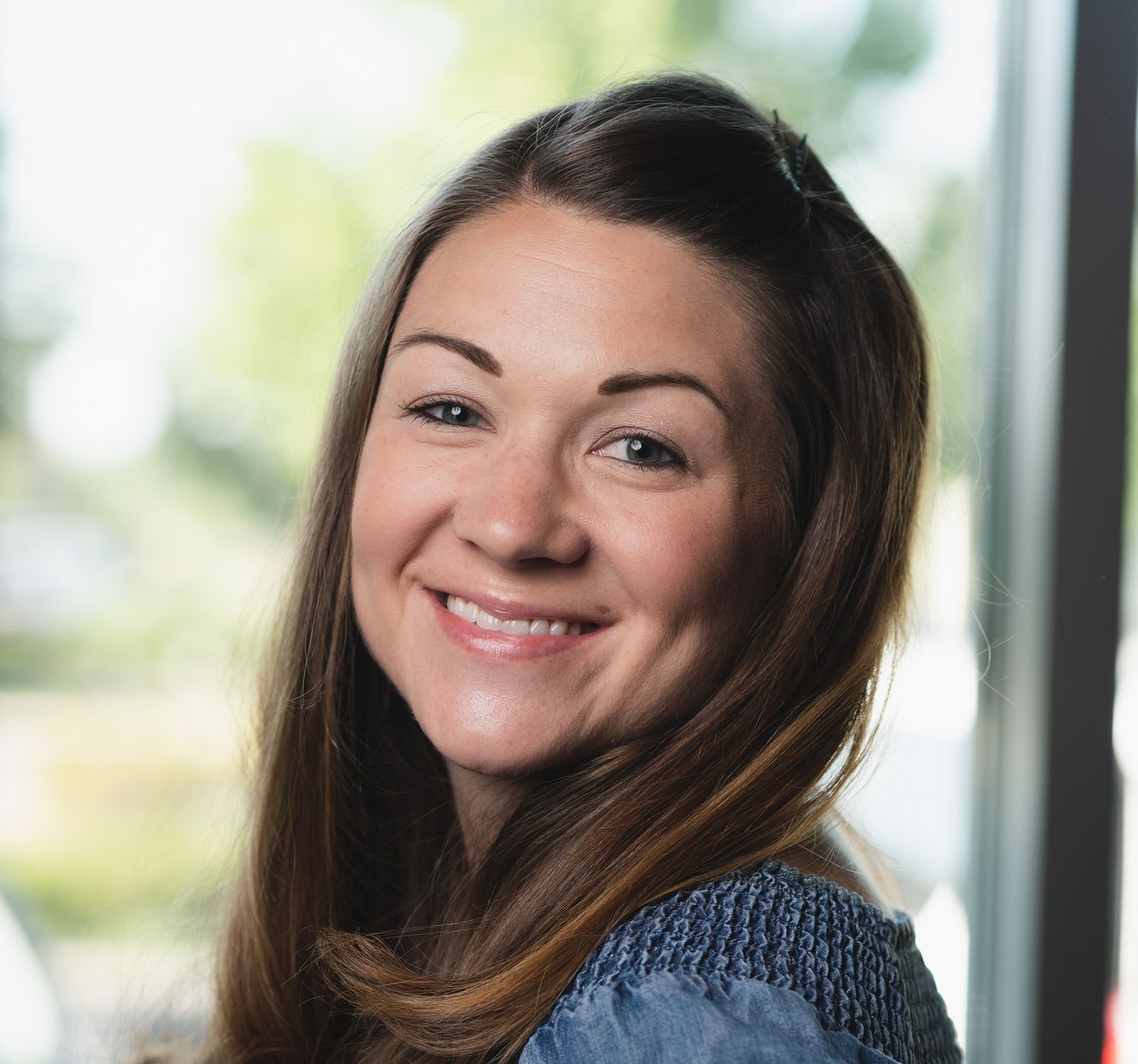 A woman with long hair is smiling and looking at the camera.