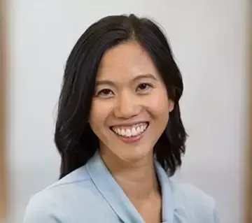 A woman in a blue jacket and white shirt is smiling for the camera.