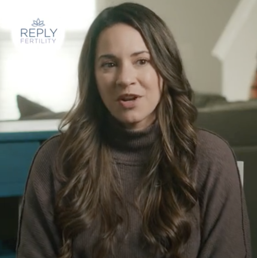 A woman with long hair is wearing a turtleneck sweater and talking.