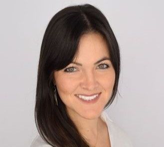 A woman in a blue shirt is smiling for the camera.