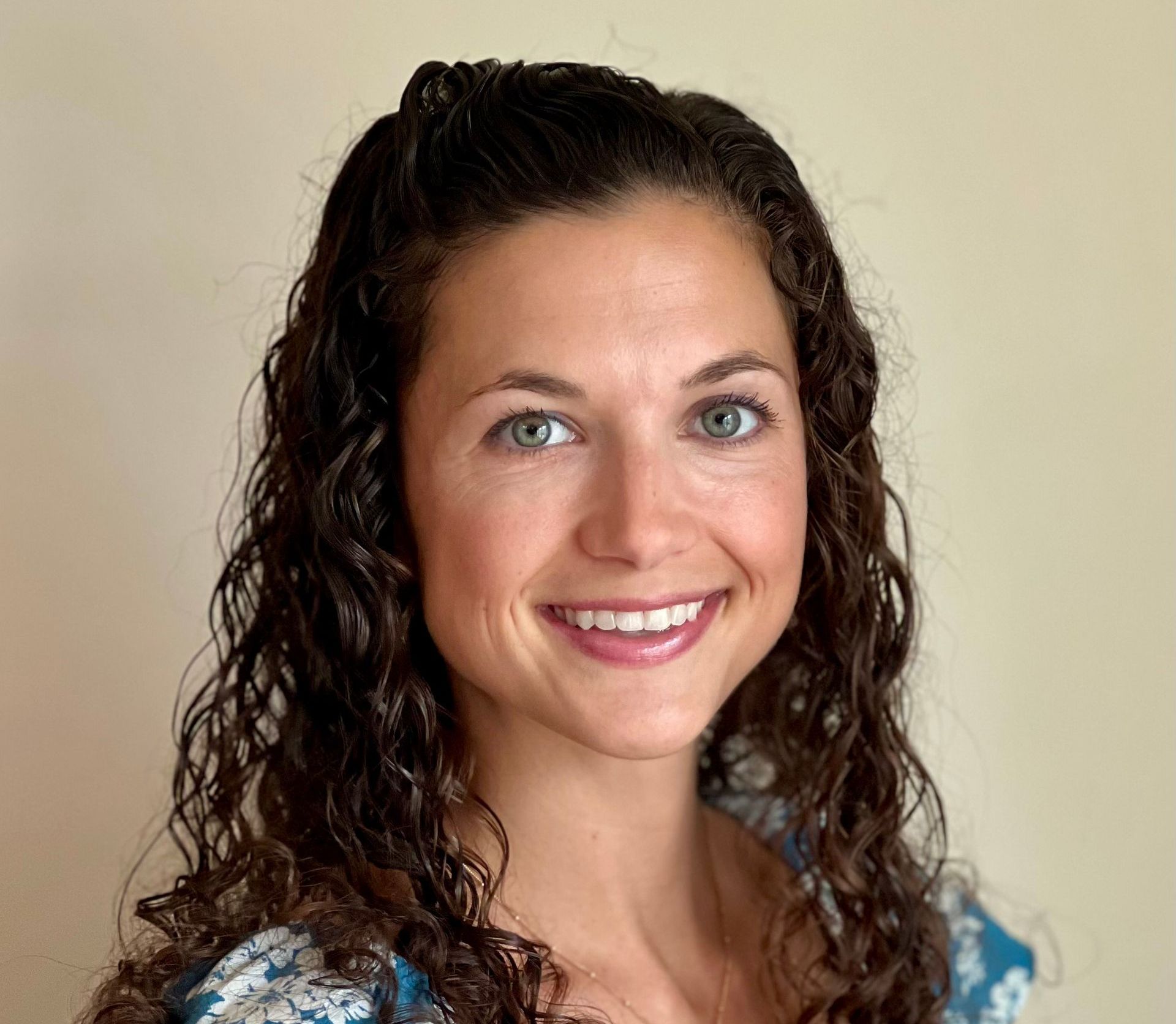 A woman in a black  jacket and white striped shirt is smiling for the camera.