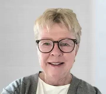 A woman wearing a striped turtleneck and earrings is smiling for the camera.